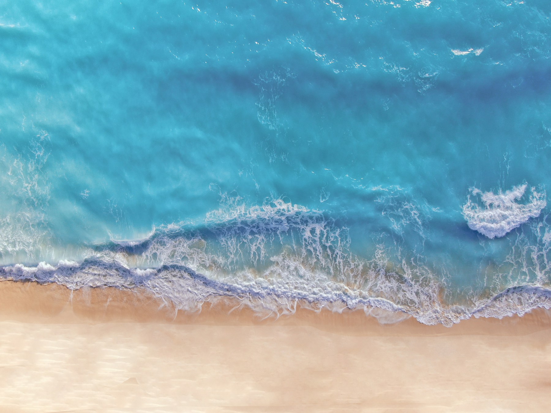 Vista aérea de olas turquesas sobre una playa de arena en Cancún, México